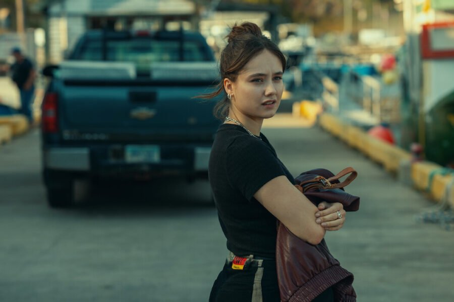 A young woman on a wharf beside parked trucks in Below