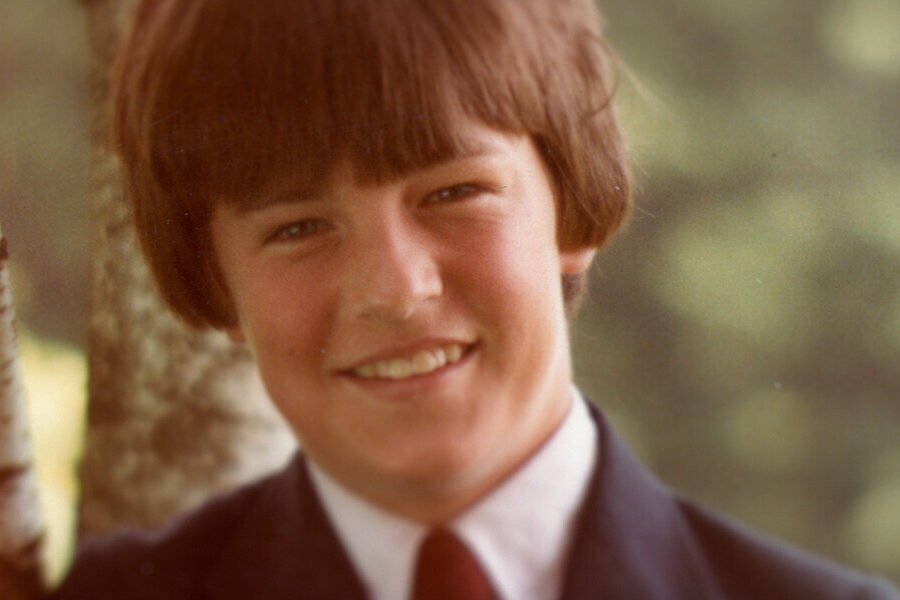 Matthew Perry as a boy in a suit and tie, standing beside a birch tree