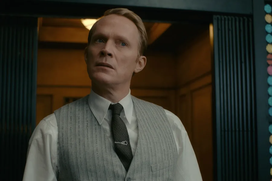 Paul Bettany as Vision stands in a doorway in a pinstriped vest printed with physics equations.
